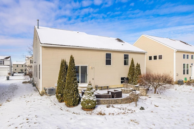 snow covered property with cooling unit and a fire pit