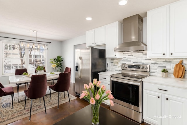 kitchen with white cabinetry, appliances with stainless steel finishes, dark hardwood / wood-style floors, pendant lighting, and wall chimney range hood