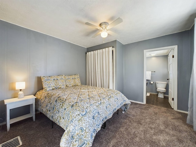 bedroom with a textured ceiling, ceiling fan, dark colored carpet, and ensuite bath