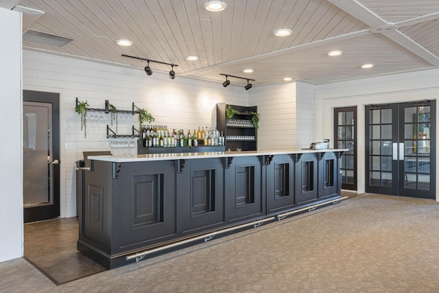 bar with wood ceiling, wood walls, dark carpet, track lighting, and french doors