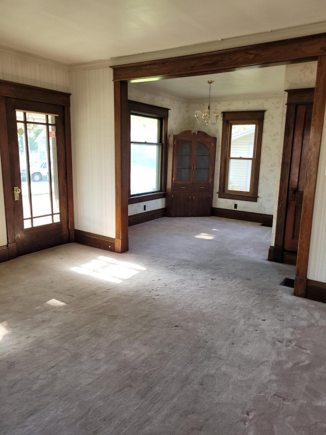 unfurnished living room featuring crown molding, carpet flooring, and a notable chandelier