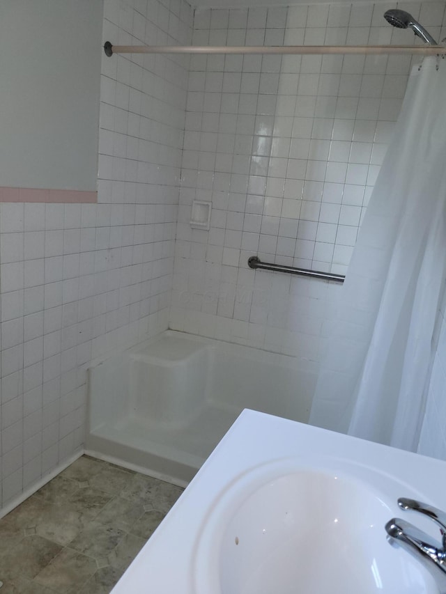 bathroom with curtained shower, sink, and tile walls