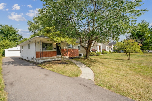 view of front facade featuring a garage, a front lawn, an outbuilding, and central AC