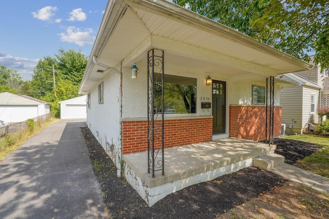 bungalow-style home featuring an outbuilding, a porch, and a garage