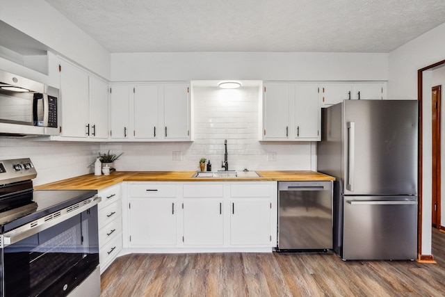 kitchen featuring appliances with stainless steel finishes, sink, white cabinetry, and a textured ceiling