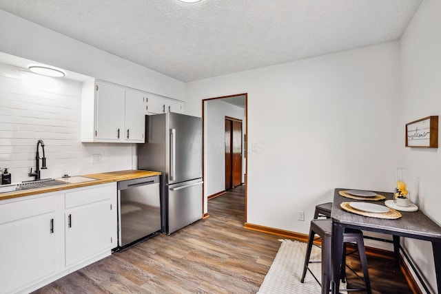 kitchen featuring light hardwood / wood-style floors, sink, appliances with stainless steel finishes, a textured ceiling, and white cabinets