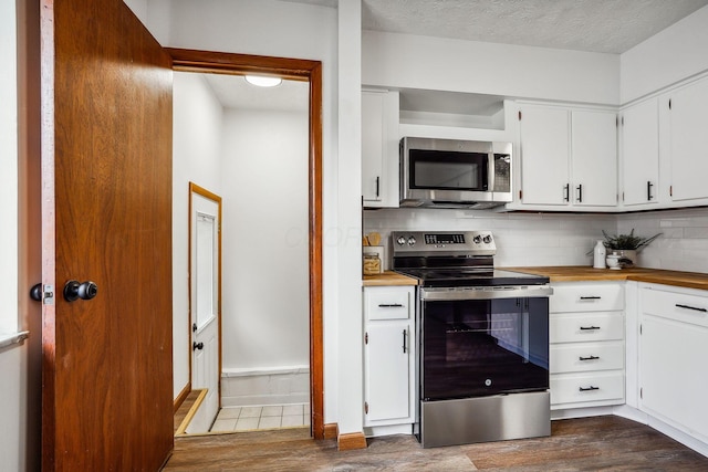 kitchen with a textured ceiling, appliances with stainless steel finishes, white cabinetry, dark hardwood / wood-style flooring, and backsplash