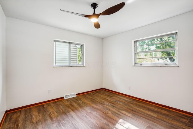 empty room with ceiling fan, a wealth of natural light, and dark hardwood / wood-style floors