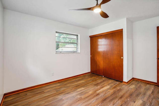 unfurnished bedroom with ceiling fan, wood-type flooring, and a closet