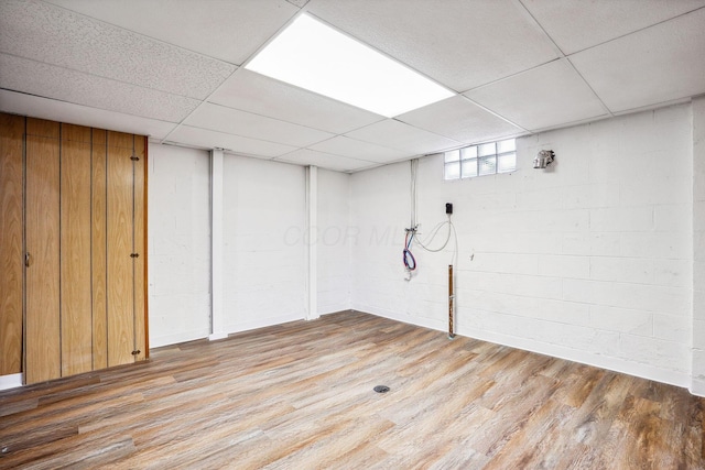 basement with a drop ceiling and light hardwood / wood-style flooring