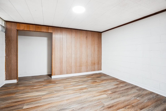 empty room featuring hardwood / wood-style floors, crown molding, and wooden walls