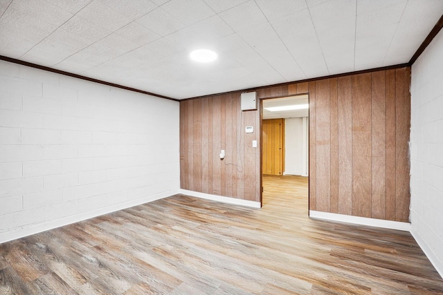 unfurnished room featuring ornamental molding, wood walls, and light hardwood / wood-style flooring