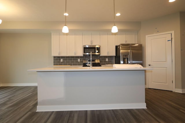 kitchen featuring appliances with stainless steel finishes, pendant lighting, and dark hardwood / wood-style flooring