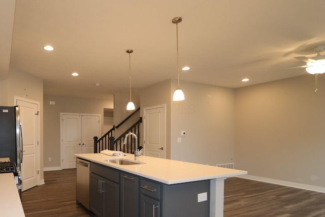 kitchen featuring appliances with stainless steel finishes, sink, hanging light fixtures, ceiling fan, and a center island with sink