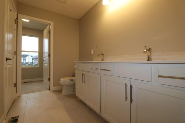 bathroom with toilet, vanity, and tile patterned flooring