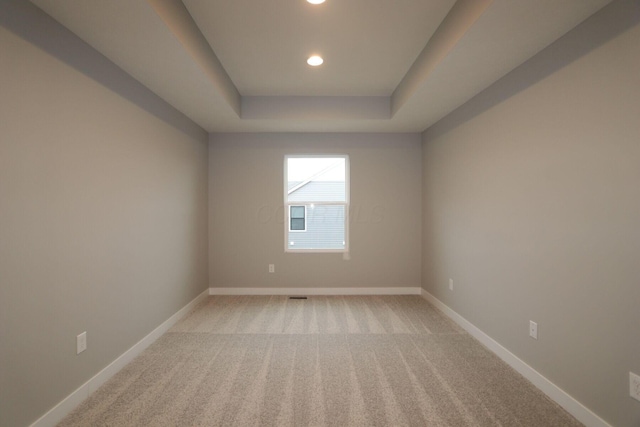 carpeted empty room featuring a tray ceiling