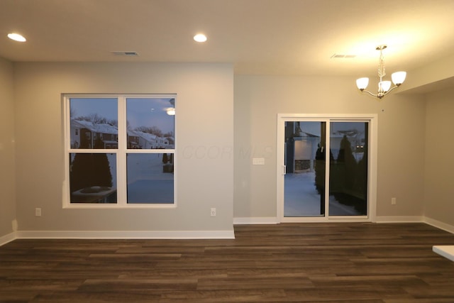 empty room featuring a notable chandelier and dark hardwood / wood-style floors