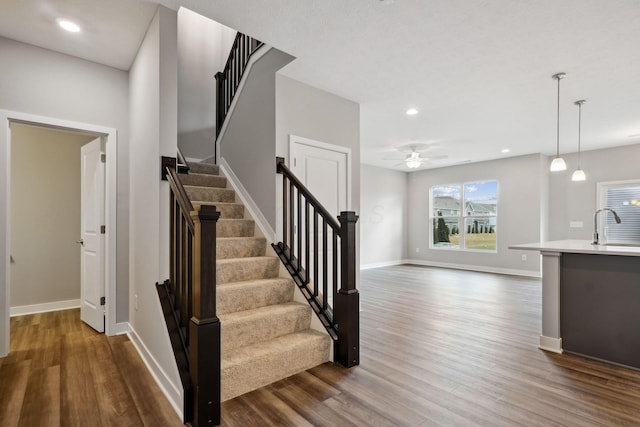 staircase featuring recessed lighting, wood finished floors, a ceiling fan, and baseboards