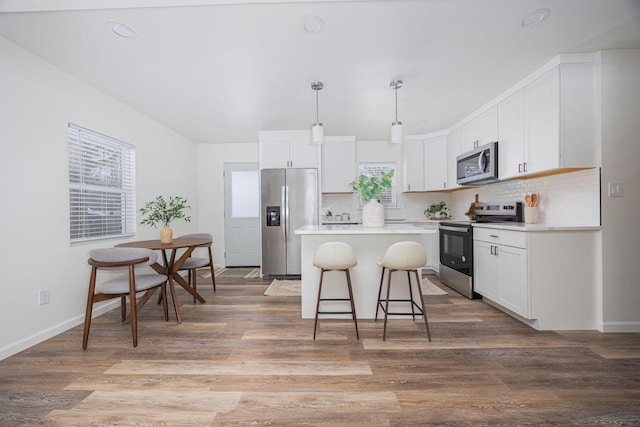 kitchen with a center island, pendant lighting, light hardwood / wood-style flooring, stainless steel appliances, and white cabinets