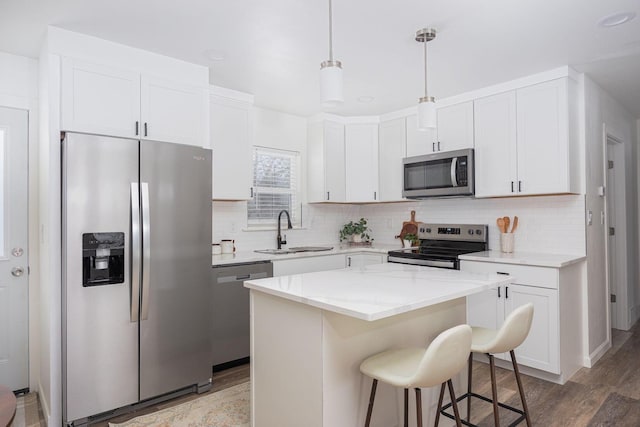 kitchen featuring white cabinetry, stainless steel appliances, a center island, and sink