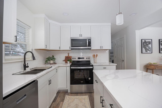 kitchen with sink, hanging light fixtures, appliances with stainless steel finishes, white cabinets, and dark hardwood / wood-style flooring