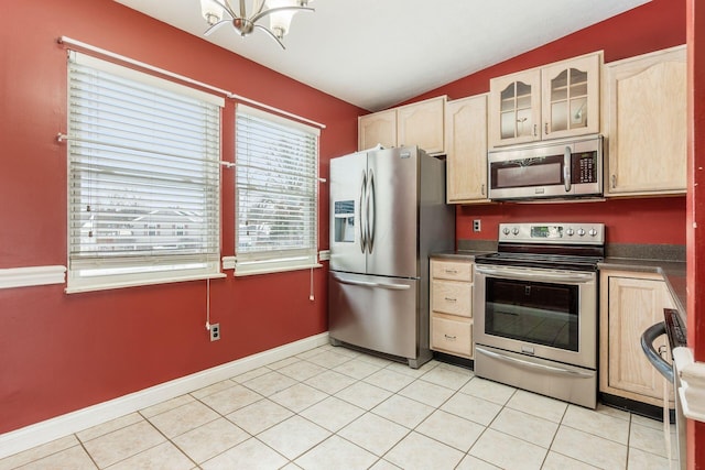 kitchen featuring stainless steel appliances, a notable chandelier, light tile patterned flooring, light brown cabinetry, and vaulted ceiling