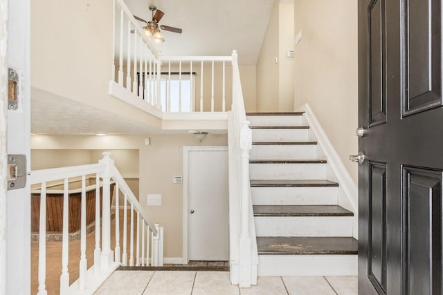 stairway featuring ceiling fan and tile patterned flooring