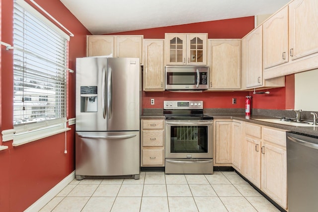 kitchen with vaulted ceiling, appliances with stainless steel finishes, light brown cabinets, and sink