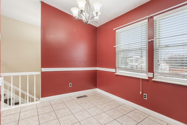 spare room featuring tile patterned flooring and a chandelier