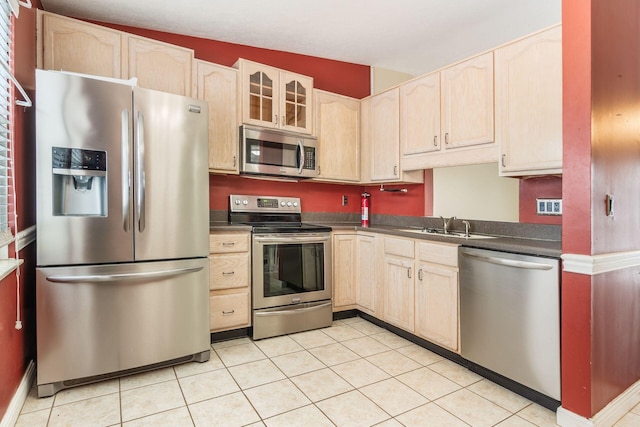 kitchen featuring light tile patterned floors, light brown cabinetry, sink, and stainless steel appliances