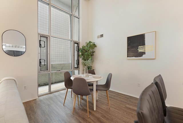 dining room with expansive windows, a towering ceiling, plenty of natural light, and dark hardwood / wood-style floors