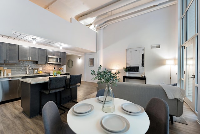 dining space featuring sink, a towering ceiling, and light wood-type flooring