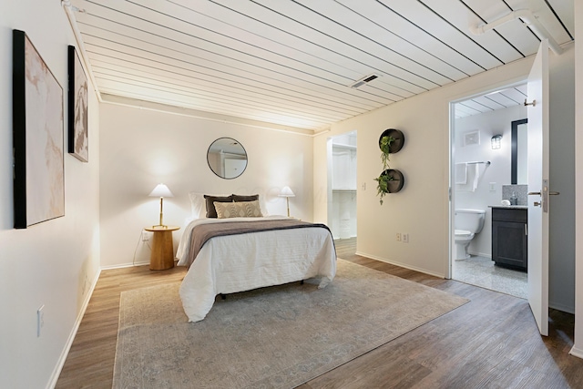 bedroom with wood ceiling, connected bathroom, and light wood-type flooring