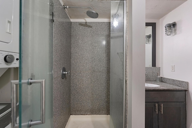 bathroom with stacked washer / drying machine, vanity, and a tile shower