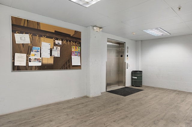 basement featuring hardwood / wood-style flooring and elevator