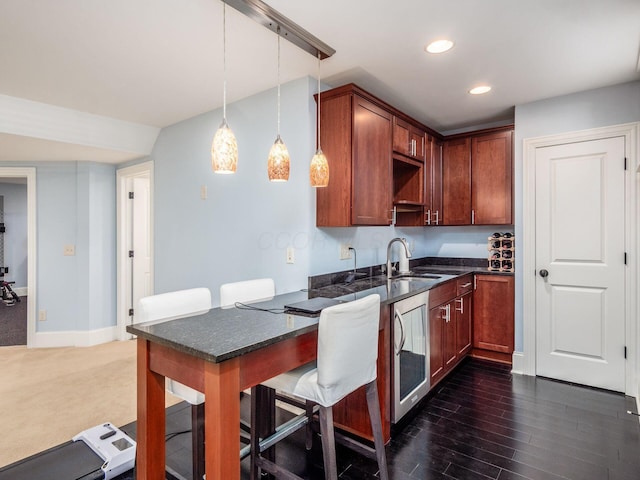 kitchen with beverage cooler, dark colored carpet, sink, hanging light fixtures, and a kitchen breakfast bar