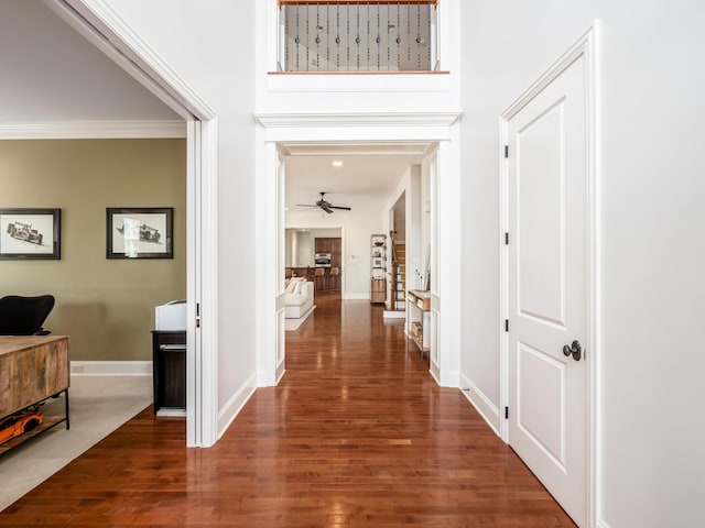 corridor with dark wood-type flooring and ornamental molding