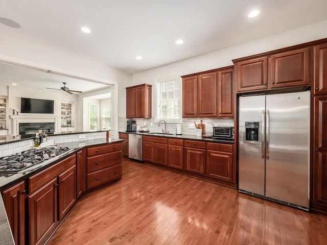 kitchen with ceiling fan, appliances with stainless steel finishes, tasteful backsplash, wood-type flooring, and sink