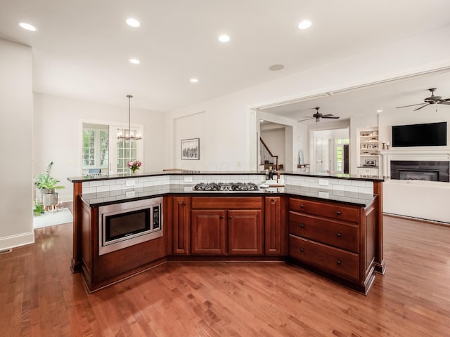 kitchen featuring pendant lighting, a center island with sink, stainless steel appliances, and light hardwood / wood-style flooring