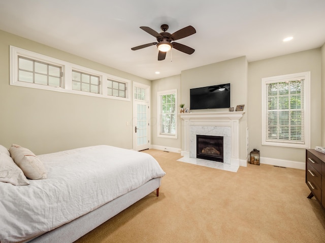 bedroom with ceiling fan, light colored carpet, and a high end fireplace