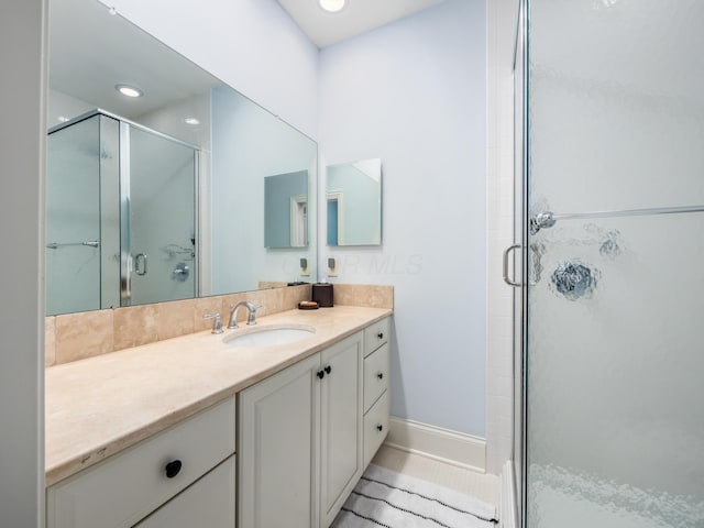 bathroom featuring a shower with shower door, vanity, and tile patterned flooring