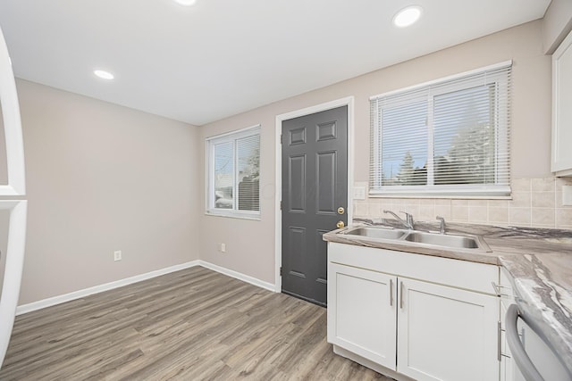 kitchen with backsplash, white cabinets, dishwasher, light hardwood / wood-style flooring, and sink