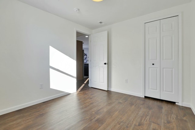 unfurnished bedroom featuring dark hardwood / wood-style flooring and a closet