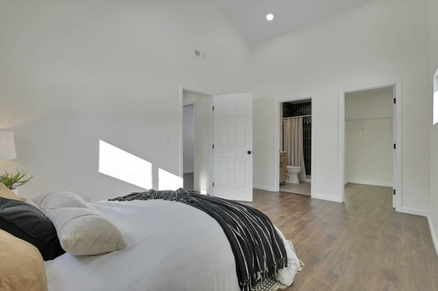 bedroom featuring ensuite bath, wood-type flooring, a spacious closet, high vaulted ceiling, and a closet