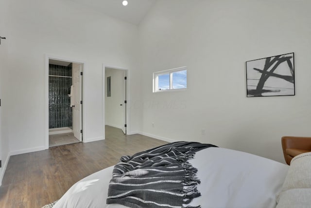 bedroom with dark hardwood / wood-style floors, connected bathroom, and a high ceiling