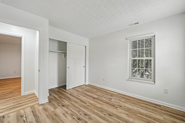 unfurnished bedroom featuring light hardwood / wood-style floors, a closet, and a textured ceiling