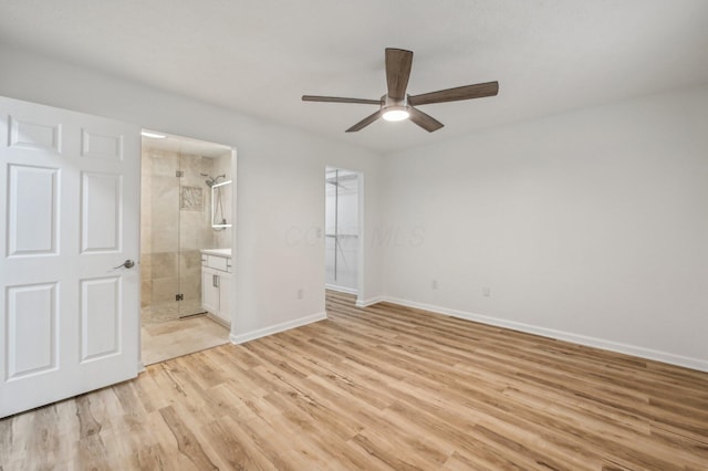 unfurnished bedroom featuring ensuite bathroom, a walk in closet, a closet, ceiling fan, and light hardwood / wood-style floors