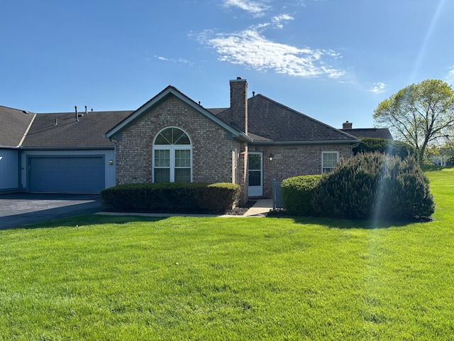 single story home featuring a chimney, a garage, brick siding, and a front yard