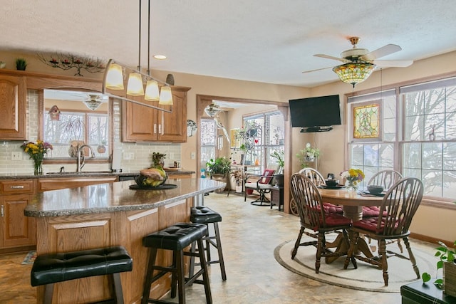 kitchen with a kitchen island, sink, decorative backsplash, light stone counters, and plenty of natural light