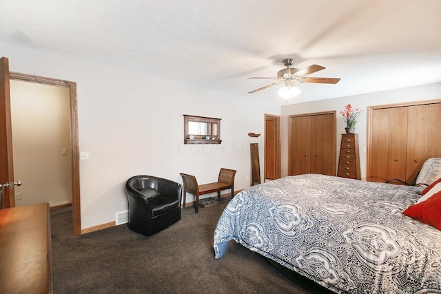 carpeted bedroom featuring multiple closets, ceiling fan, and a textured ceiling